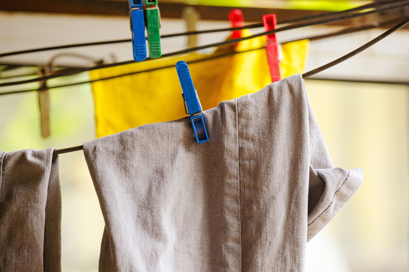 Laundry hanging from a clothesline with colored pegs, illustrating air drying for suitable garments.